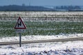 Snowy countryside landscape with sunshine and a road sign, dangerously slippery