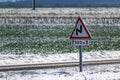 Snowy countryside landscape with sunshine and a road sign, dangerously slippery