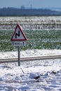 Snowy countryside landscape with sunshine and a road sign, dangerously slippery