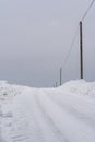Snowy Countryside Road with Snow Piles and Power Lines Aside