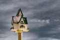 Snowy-covered birdhouse close up with cold winter sky on background