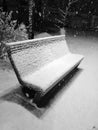 Snowy day in the park. Wooden bench in the snow on a snowy evening. Snowfall in the recreation park