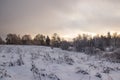 Snowy field at sunset in winter. Beautiful sky. The sky before the snow. Gray sky and sun. Evening sun Winter sunset Royalty Free Stock Photo