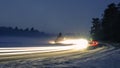 Snowy foggy forest road with trails from car lights. Royalty Free Stock Photo