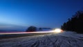 Snowy foggy forest road with trails from car lights. Royalty Free Stock Photo