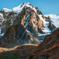 Snowy high-altitude alpine landscape with snow-capped mountain peak and sharp rocks under blue sky Royalty Free Stock Photo