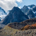 Snowy high-altitude alpine landscape with snow-capped mountain peak and sharp rocks under cloudy blue sky Royalty Free Stock Photo