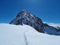 Snowy hiking trail with footsteps leading to a mountain peak