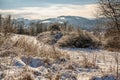 Snowy hillside with frozen vegetation, hills and houses on background, Zlin