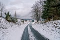 Snowy icy road among the forest on the edge of a small village Royalty Free Stock Photo