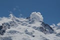 Snowy summit of Dufourspitze mountain with cumulus cloud, blue sky Royalty Free Stock Photo