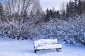 Snowy landscape. The park bench is covered with white thick snow. Royalty Free Stock Photo