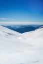 Snowy landscape on the top of a mountain, in the background other mountains melting against the horizon with a clear sky Royalty Free Stock Photo