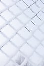 Snowy mesh fence made of steel with blue sky and blurred tree in background constraining unknown area. Exile to Siberia