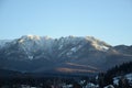 Snowy mountain and houses surrounded by trees under the plain blue sky Royalty Free Stock Photo