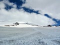 Snowy mountain valley, covered with gray clouds. Barely noticeable silhouettes of people walking through the valley