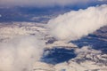 Snowy mountains background and white clouds above them. Aerial photo from plane`s window. Royalty Free Stock Photo