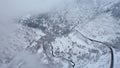 Snowy mountains with coniferous trees in clouds