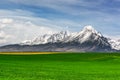 Snowy mountains peaks and green field in spring High Tatras