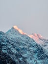 Snowy mountains with rays of the sun on the background of a gray sky