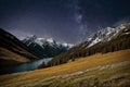 Snowy mountains and starry sky reflected in a blue lake at night Royalty Free Stock Photo