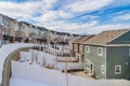 Snowy neighborhood landscape of home with backyards and townhouses along road