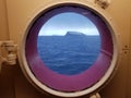 Snowy ocean island isolated in the middle of the sea in northern norway, seen through a ships window hull