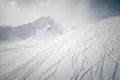 Snowy off-piste ski slope with ski and snowboard tracks on a sunny winter day. Freeride in high mountains Royalty Free Stock Photo