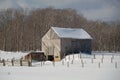 Snowy old barn with diagonal boards and barnyard Royalty Free Stock Photo