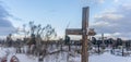 Snowy old broken grave wooden cross shaped on dramatic sky background. Orthodox traditional cemetery in snowy winter Royalty Free Stock Photo