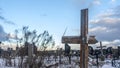 Snowy old broken grave wooden cross shaped on dramatic sky background. Orthodox traditional cemetery in snowy winter Royalty Free Stock Photo