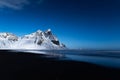 Snowy peaks lit by full moon light on a lonely calm clear blue night at Stokksnes beach in Iceland Royalty Free Stock Photo