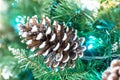 Snowy Pine Cones On Spruce Branch With Lights. Christmas or New Year blurred background with festive fir tree and pine cones, Royalty Free Stock Photo