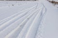 Snowy road in a field leading to pine forest. Winter road to nowhere in sunny day, snow-covered fresh car track. Car Royalty Free Stock Photo