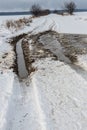 Snowy road in a field leading to pine forest. Winter road to nowhere in sunny day, snow-covered fresh car track. Car Royalty Free Stock Photo