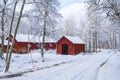 Snowy road by red barns in a wintry landscape Royalty Free Stock Photo