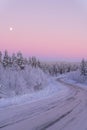 a snowy road surrounded by trees under the moon at dusk Royalty Free Stock Photo