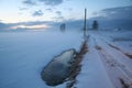 Snowy roadside and a cloudy sky on a misty cold winter day