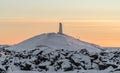 Snowy rocky mountain with Reykjanesviti lighthouse on it during sunset
