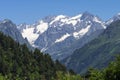 Snowy rocky mountains peaks and forest on blue sky background on sunny summer day. Caucasus mounts. Mountain landscape. Royalty Free Stock Photo