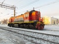 Snowy Russian Railways shunting diesel locomotive on snowy railway truck with railway station in the background. Railways winter