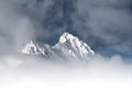 Snowy snow-capped rock mountain peaks protrude from fog soup