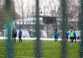Snowy soccer field in December, frost and cold weather. Young people play football. Selective focus