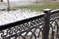 Snowy spring park with a fence