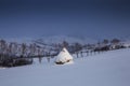 Snowy straw stack on a hillside with mountains in the background Royalty Free Stock Photo