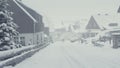 Snowy street of mountain town, snow calamity. Winter landscape with falling snow.