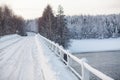 Snowy surface of empty country road on bridge across a river, winter season Royalty Free Stock Photo