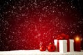 Snowy table top with space for products and christmas decorations and red burning candles and baubles with snowy background. Royalty Free Stock Photo