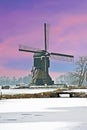 Snowy traditional windmill in the countryside from the Netherlands at sunset