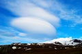 Snowy volcanic mountain and interesting shaped clouds in a sunny day